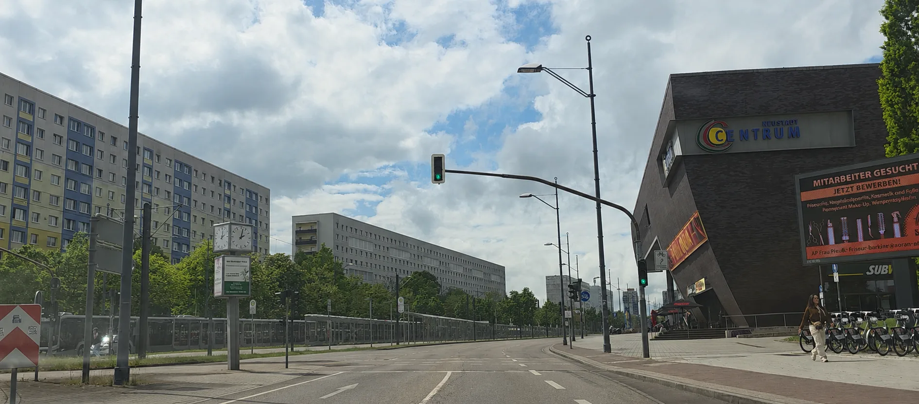 In diesem lebendigen Teil der Straße An der Magistrale befindet sich das Centrum-Neustadt auf der rechten Seite des Bildes. Auf der linken Seite sieht man die Wohngebäude. Dazwischen gibt es eine Straßenbahnhaltestelle.