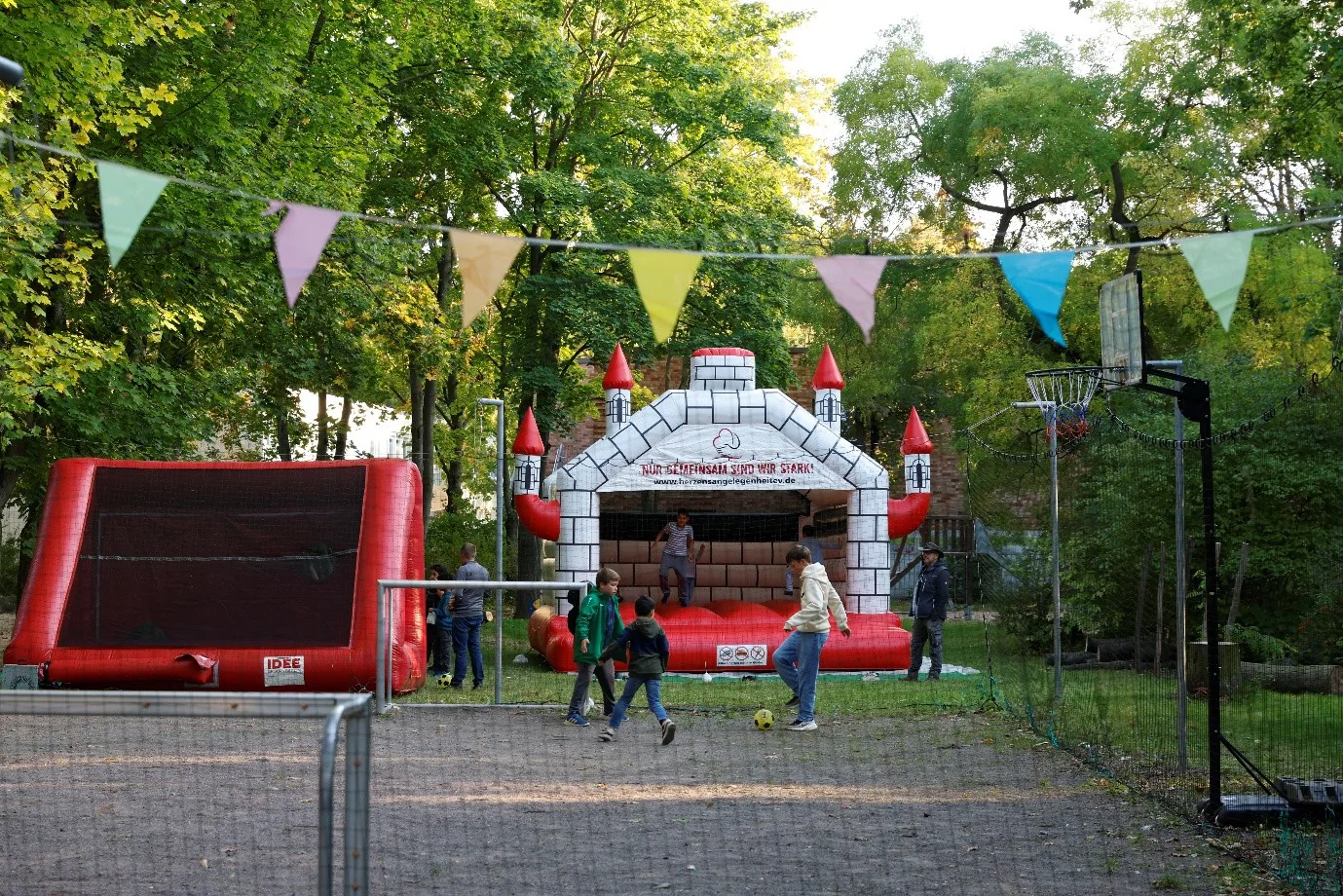 Im Garten des Hoertes ist eine Hüpfburg aufgebaut. Davor hängt eine bunte Girlande.